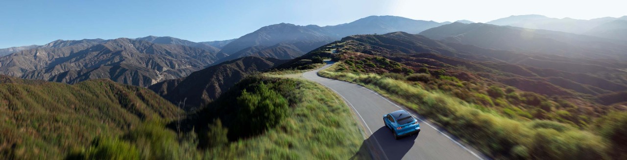 A Ford Mustang MachE is driving on a mountain road